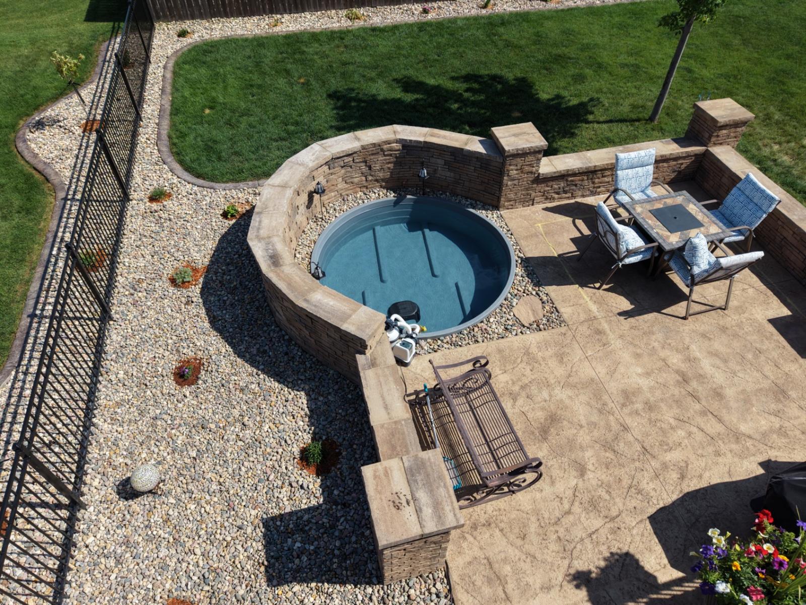 Overhead drone shot of the custom stock tank pool surround with stacked stone wall and stamped patio