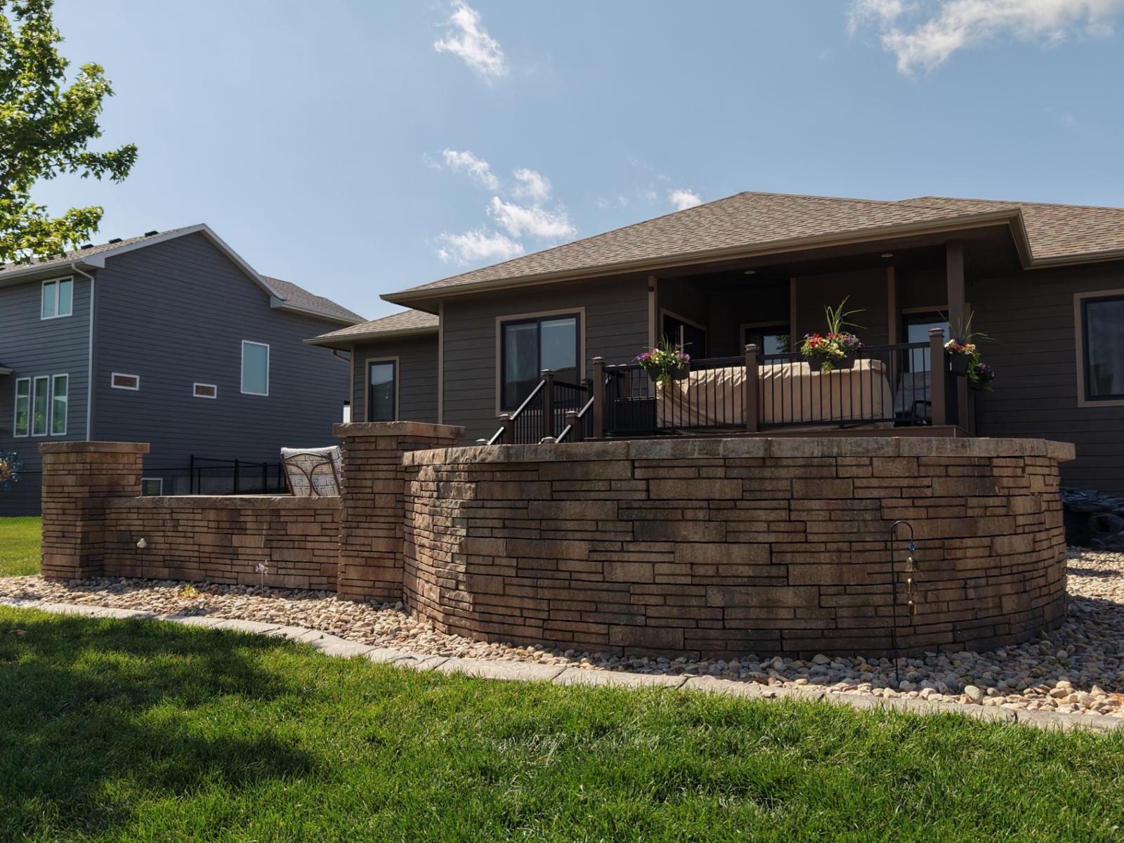 Curved stacked-stone seat wall wrapping an elevated deck — Kerwin build