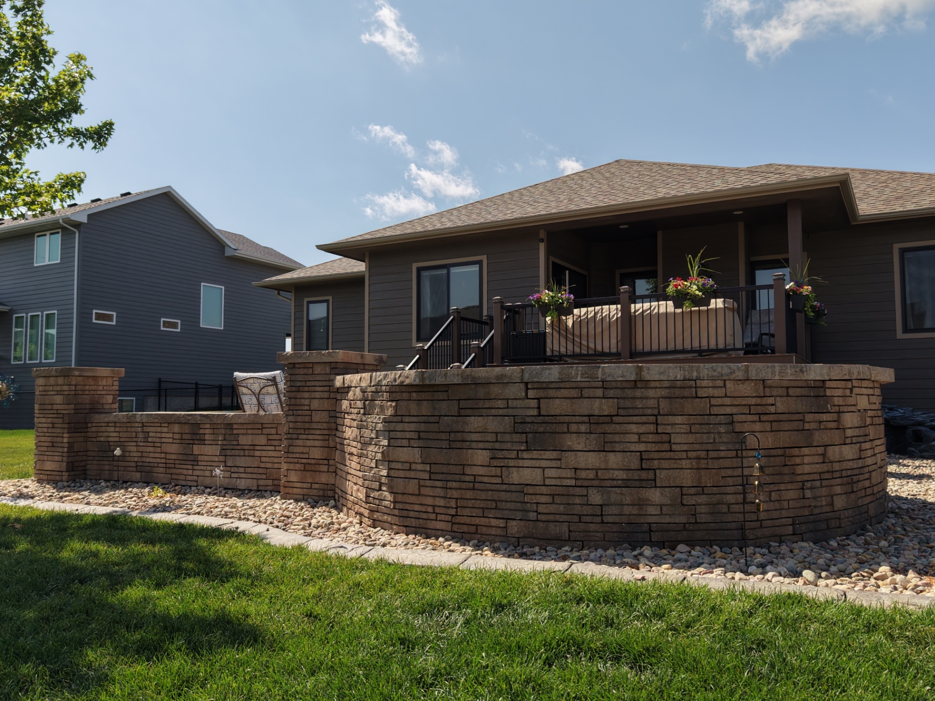 Curved stacked-stone seat wall wrapping an elevated deck — Kerwin build